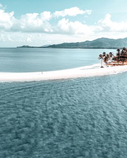 A gorgeous vertical shot of a narrow white beach surrounded by calm blue water at Koh Yao Yai, Thailand