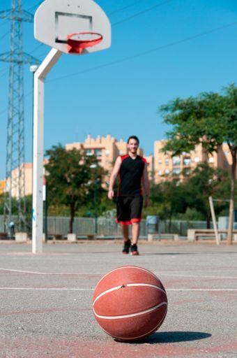 A vertical shot of a ball on a basketball court with a man playing