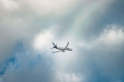 A low angle of a plane takeoff, an airplane caught mid flight just as the landing gear was taken up