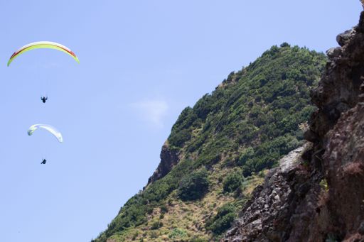 A beautiful view of two people paragliding over the mountains against a blue sky