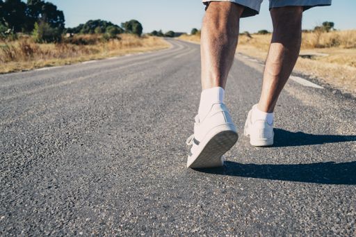 Close-up of an elderly man's legs walking down the road. Concept of vitality