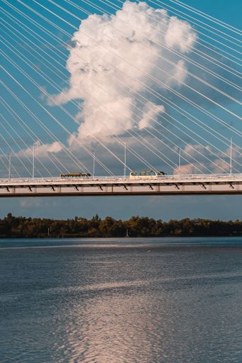 The vertical partial view of a bridge over water on a sunny day