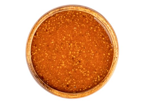 An isolated shot of a wooden bowl full of bavarian mustard on a white background