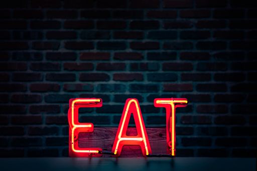 A closeup shot of a turned-on KISS neon-light signage with the background of a brown brick wall