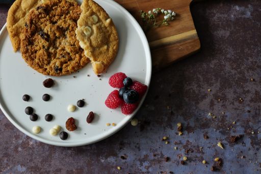 A closeup shot of a plate with freshly baked cookies and berries on a wooden table