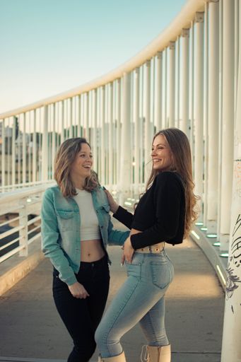Two Hispanic girls dressed in casual clothes, smiling and posing outdoors on a sunny day, the concept of fashion