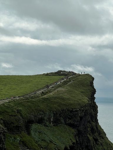 A vertical shot of a huge cliff in the cloudy sky