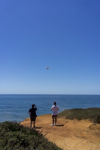 A young male operating a drone with remote near the ocean in Cadiz, Andalucia, Spain