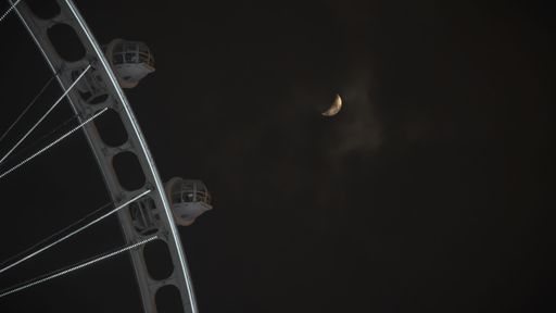 The moon at the night sky with Ferries wheel in the foreground