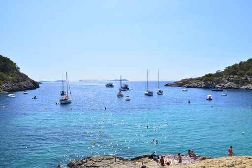A high angle shot of boats in the sea and cliffs