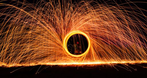 A dramatic glowing long exposure of  spinning light trails with sparks