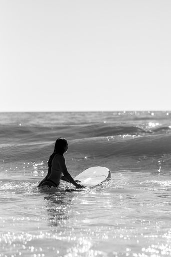 A greyscale shot of a female surfing on the waves at Cadiz, Andalucia, Spain