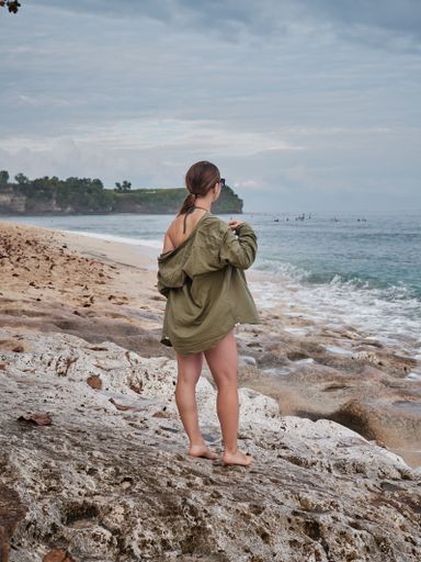 A pretty Caucasian woman in a swimsuit posing at the sandy beach with the blue sea in the background