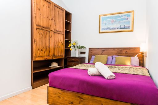 A wooden bed and shelf in a bedroom with white walls