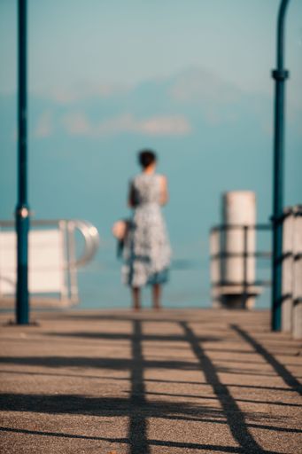 A vertical ground-level shot of a road near seashore with a female standing at the end of it