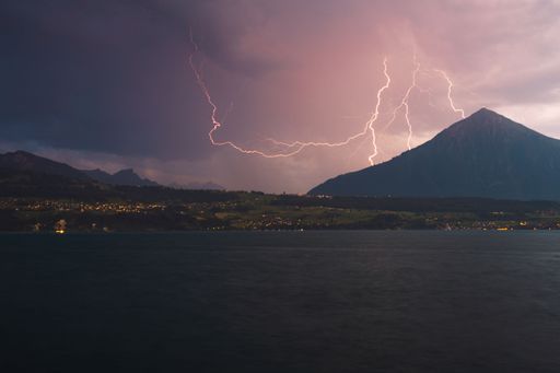A high hill near a lake under the cloudy sky in the evening in Merligen, Switzerland