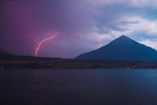 A high hill near a lake under the cloudy sky in the evening in Merligen, Switzerland