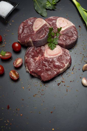 A vertical closeup shot of raw fresh meat steak and seasonings on dark background