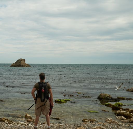 A shot of a tourist standing near the sea