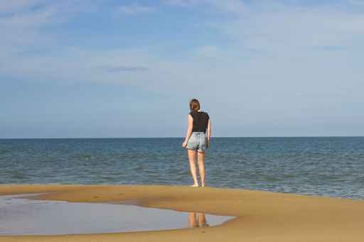 A young female standing and looking out over the ocean at Bethany Beach, Delaware