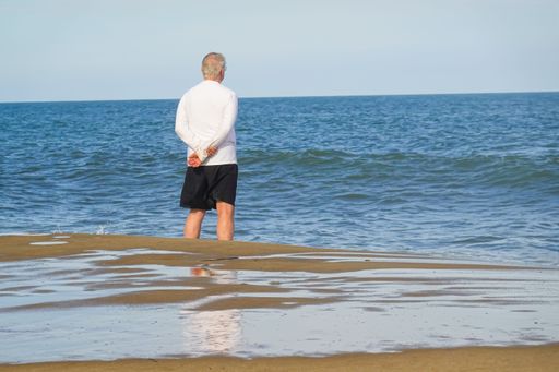 A rear shot of an old man looking at the sea horizon from the beach in Bethany Beach, DE