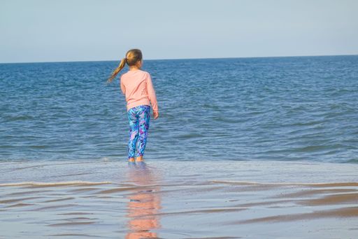 A young girl standing and looking out over the ocean at Bethany Beach, Delaware