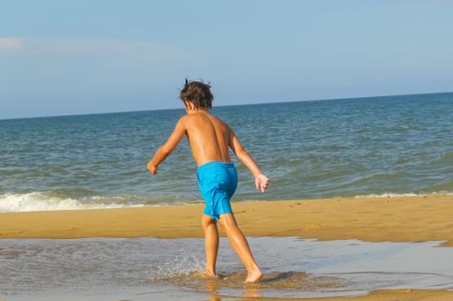 A Caucasian boy running along sea waves at Bethany Beach, Delaware