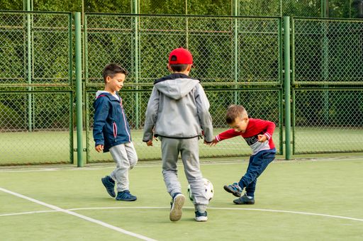 Group of young boys playing soccer with a football on a public sport field