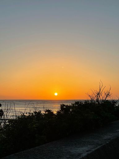 A vertical shot of a bright orange sunset sky over a lake