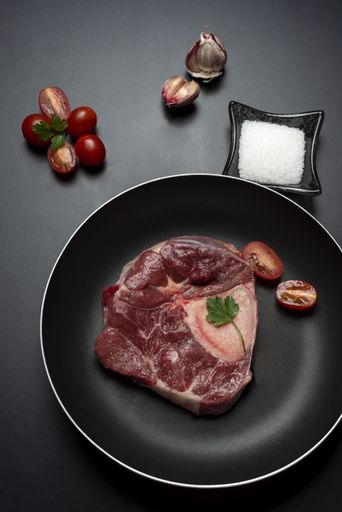 A vertical closeup shot of raw fresh meat steak and seasonings on dark background