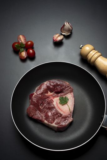 A vertical closeup shot of raw fresh meat steak and seasonings on dark background