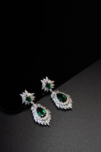 A vertical shot of beautiful green earrings isolated on a dark background