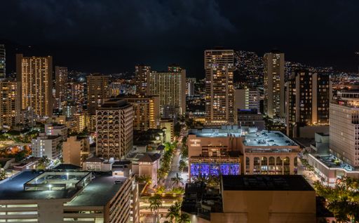 An aerial shot of modern buildings with the lights on during the nighttime in Hawaii, United States.