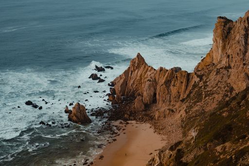 The aerial view of waves reaching the cliffs of Cabo da Roca on a sunny day