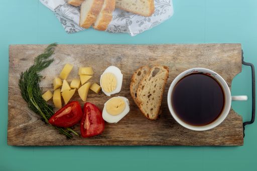 A rustic wooden cutting board with freshly prepared breakfast and a cup of coffee