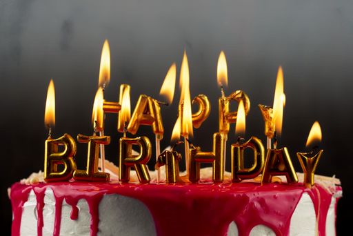 A delicious-looking red cake with burning birthday candles with the words 'Happy Birthday