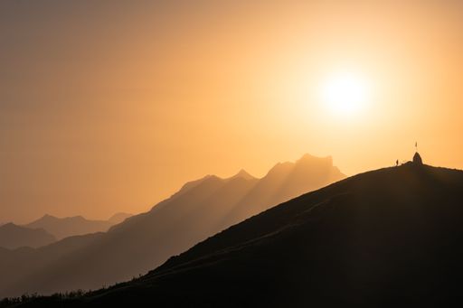 The silhouette of a man by a flag in the Swiss Alps at sunset