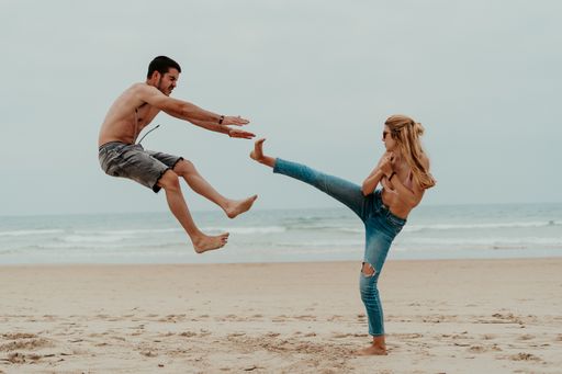 A male VS female competition - a female making a karate movement and hitting the male causing him to fall