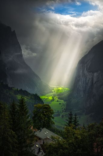 A vertical breathtaking scenery of the sun rays shining through the clouds against the mounts
