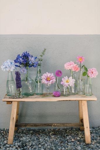 A beautiful shot of assorted colorful flowers in individual vases on a wooden table