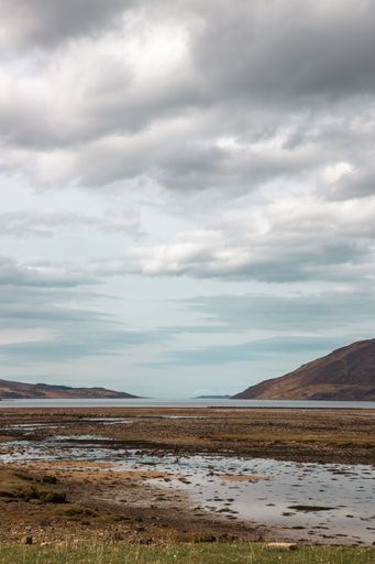 a Vertical Beautiful shot of water near misty scottish highlands