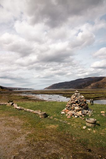 a vertical shot of some rocks piled up near a body of water in scottish highlands