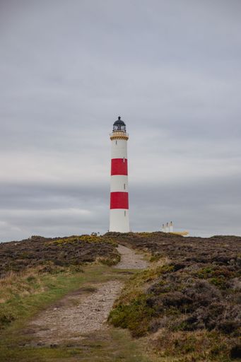 A vertical shot of a path leading up to the Tarbatt Ness Lighthouse in Scotland on a cloudy day