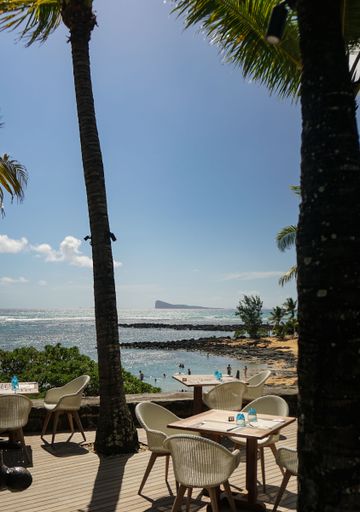View from a hotel over the beach and sea with chairs in the foreground and blue sky