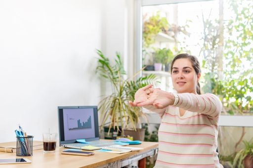 A woman stretching and exercising in an office setting, seeking relief from a sedentary position