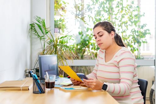 A young female professional is sitting at a desk, focused on a yellow hardcover book in front of her
