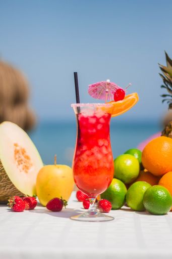 A perfect tropical cocktail with a paper parasol and fresh fruits on a beach
