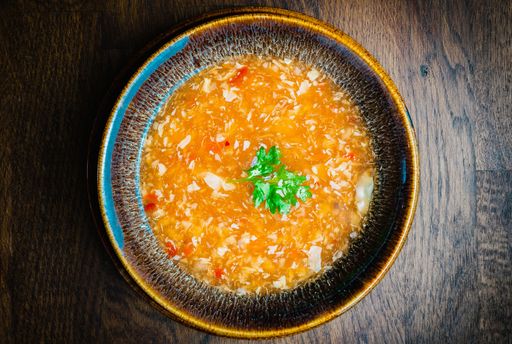 A top view of a bowl of gourmet Asian crab soup on a wooden table