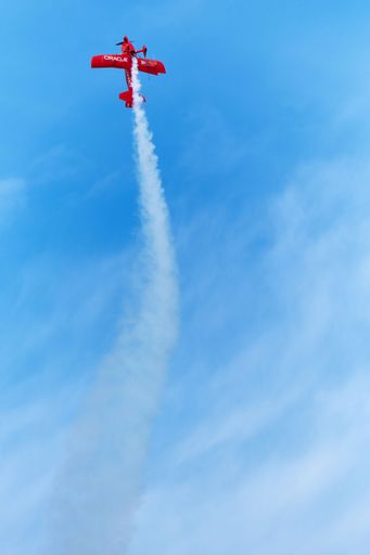 A vertical low angle shot of a small red private aircraft in flight in Houston city US