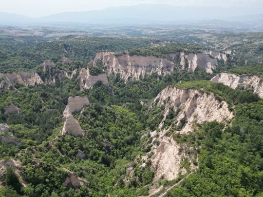 An aerial shot of the pyramids of Melnik and green trees on a summer day, Bulgaria